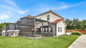 Une maison dotée d’un grand patio vitré, d’une piscine et d’une pelouse bien entretenue.
