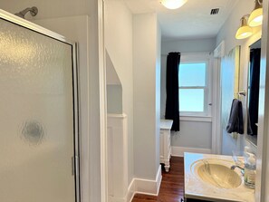 A bathroom with a white sink, a mirror, and a window with a black curtain.
