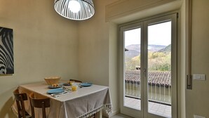 Un comedor con una mesa preparada para dos personas, un bol, platos y un vaso de jugo de naranja.