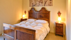 A bedroom with a wooden bed, two bedside tables, a wooden ceiling, and wall-mounted artwork. - Appartamento Billy by Theater Home - with partial lake view and garage (Tignale)