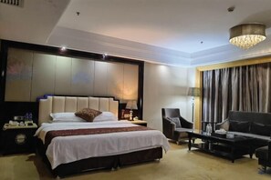 Una habitación de hotel con una cama grande, un sofá, una silla, una mesa de centro y un candelabro.