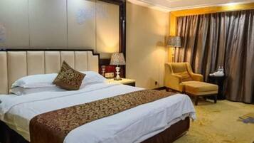 A hotel room with a large bed, a chair, a nightstand, and a lamp.