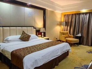 A hotel room with a large bed, a chair, a nightstand, and a lamp. - Weihua Internationai Hotel (Hui'an)