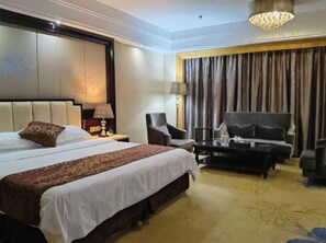 Una habitación de hotel con una cama grande, un escritorio, una silla y un sofá.