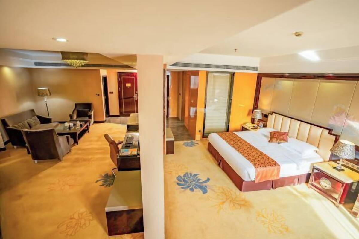 Una habitación de hotel con cama, escritorio, silla y sofá.