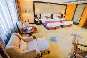 A hotel room with a sofa, a small table, a bed with two pillows, and a nightstand with a lamp. - Weihua Internationai Hotel (Hui'an)