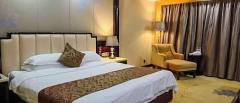 A hotel room with a large bed, a chair, a nightstand, and a curtain.
