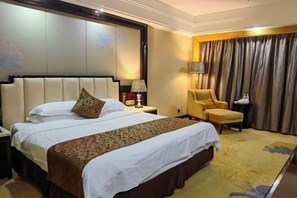 Una habitación de hotel con una cama grande, una silla, una mesita de noche y una cortina.