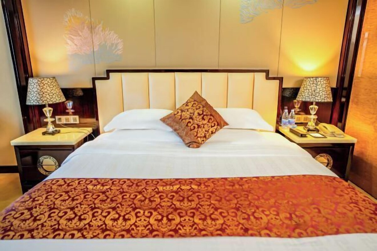 A hotel room with a large bed, two nightstands with lamps, and a decorative pillow.