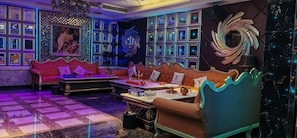 A room with a checkered floor, a red sofa, a blue sofa, and a table with various items. - Weihua Internationai Hotel (Hui'an)
