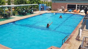 A swimming pool with lounge chairs and a covered seating area. - Debbie's Suites and Apartments  (Orozo)