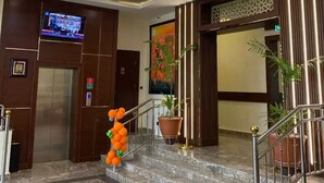 A hotel lobby with a marble staircase, a television mounted on the wall, and a large potted plant. - Debbie's Suites and Apartments  (Orozo)