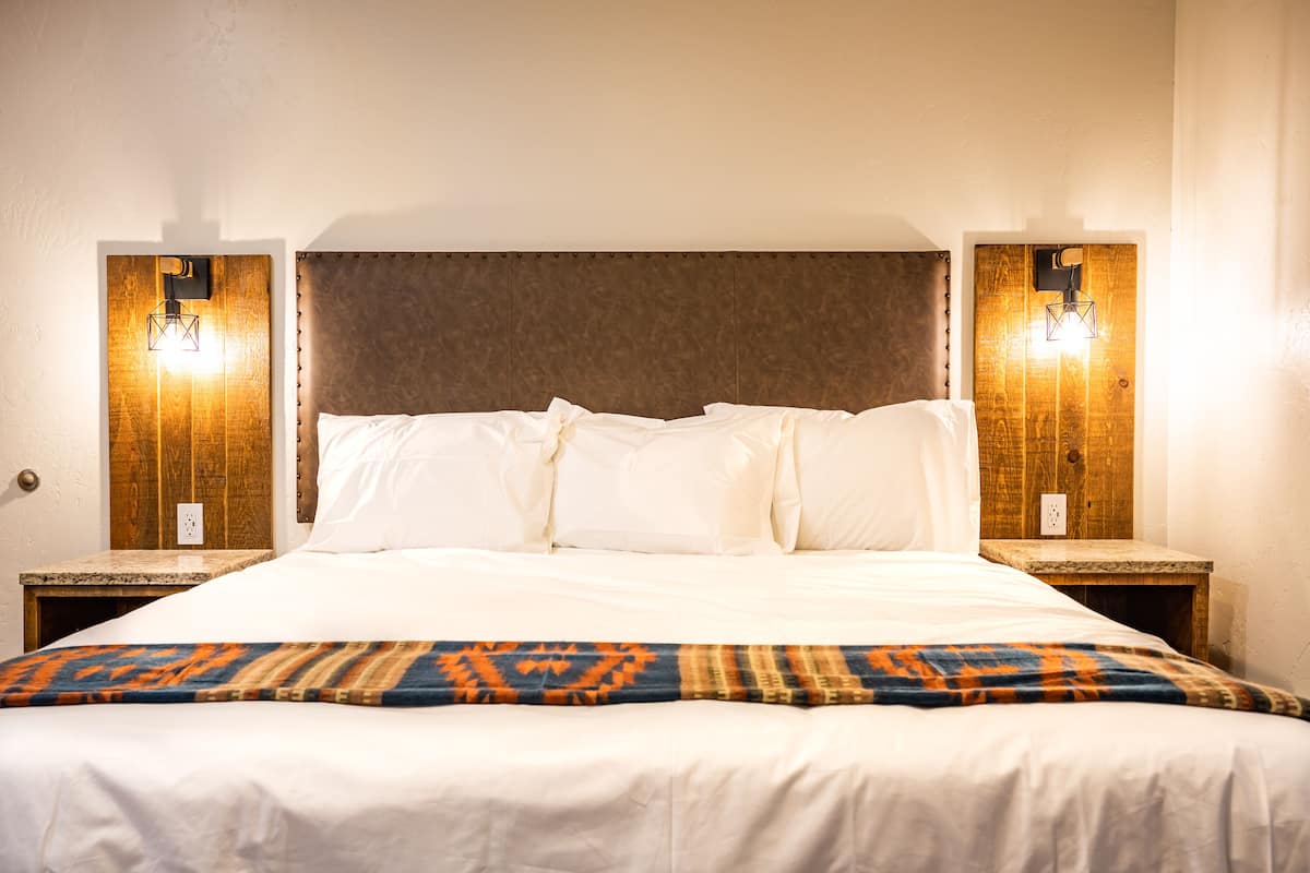 A hotel room with a large bed, two nightstands, and a wooden headboard.