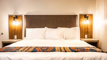 Habitación de hotel con una cama grande, dos mesitas de noche y un cabecero de madera.