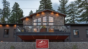 A modern hotel with a stone facade, large windows, and a balcony with outdoor seating. - Grand Cloudcroft Hotel (Cloudcroft)