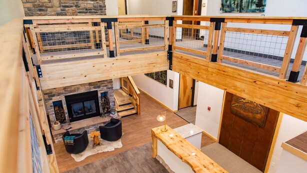 A multi-level wooden interior with a fireplace, seating area, and a wooden bench. - Grand Cloudcroft Hotel (Cloudcroft)