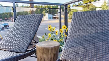 Two wicker lounge chairs with a wooden post and a potted plant with yellow flowers.