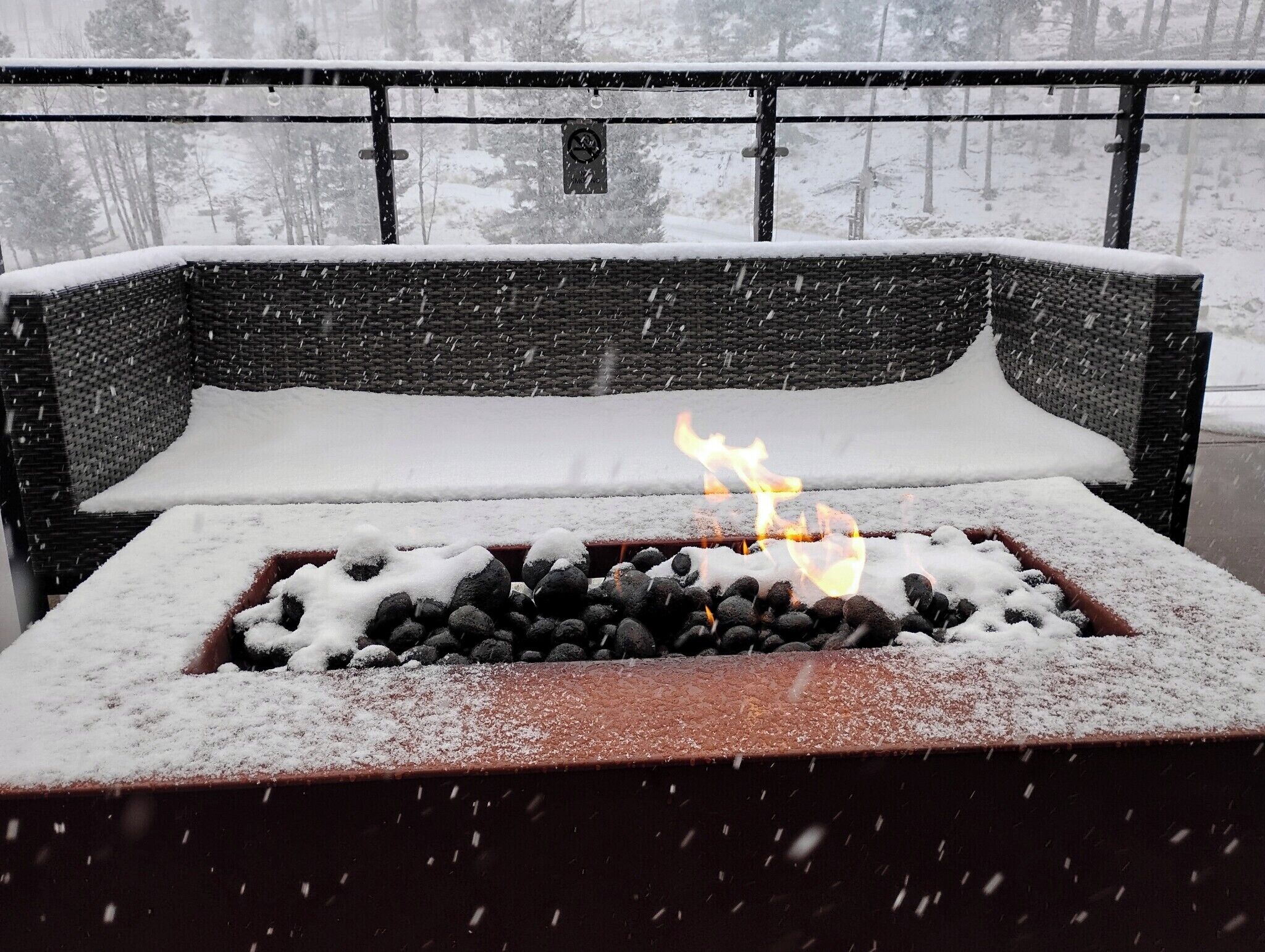 Ein mit Schnee bedeckter Außenbereich mit Sitzgelegenheiten und einem Feuerkorb in der Mitte.