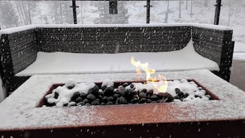 A snow-covered outdoor seating area with a fire pit in the center.