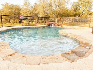Una piscina amb un videt de pedra i una zona tancada per una tanca.
