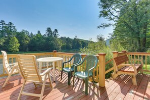 Eine Holzterrasse mit Tisch und Stühlen mit Blick auf einen See, umgeben von Bäumen.