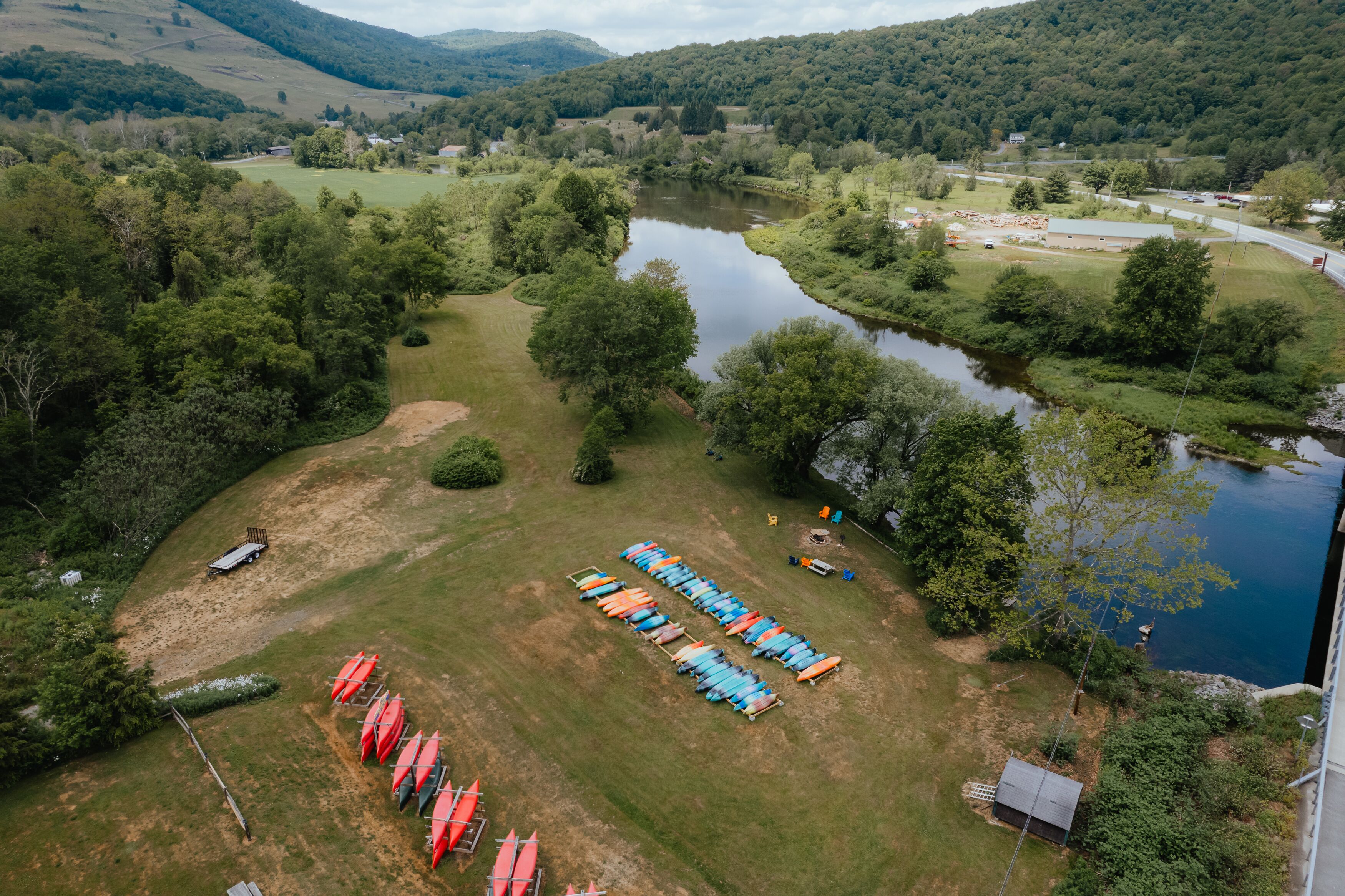 An aerial view of a riverside campsite with tents and canoes.