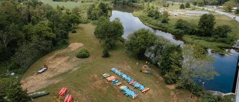 An aerial view of a riverside campsite with tents and canoes.