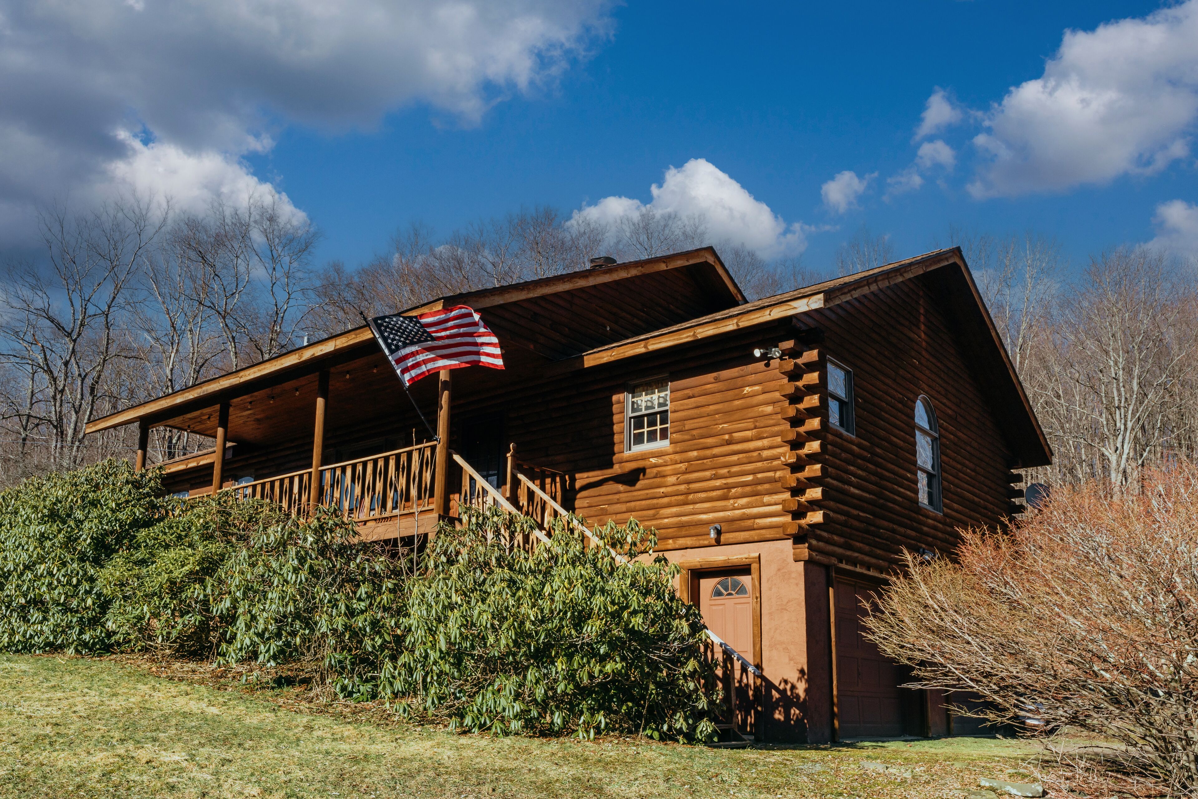 A log cabin with a porch and an American flag.