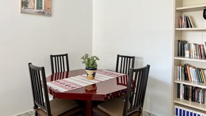 A dining area with a wooden table, four chairs, a potted plant, and a bookshelf. - Bright and quiet apartment near the sea (Saint-Raphaël)