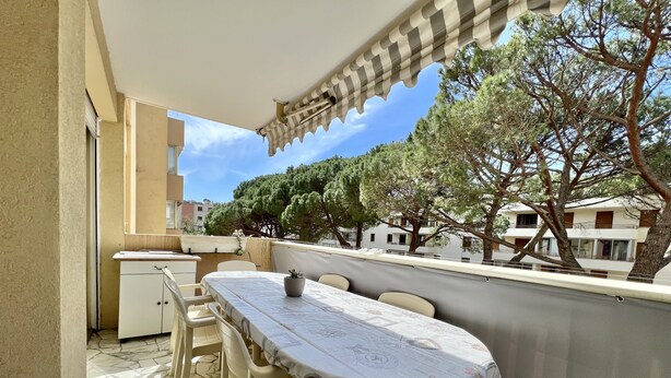 An outdoor balcony with a dining table, chairs, and a small cabinet. - Bright and quiet apartment near the sea (Saint-Raphaël)