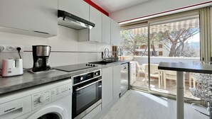A modern kitchen with a built-in oven, a coffee maker, and a washing machine. - Bright and quiet apartment near the sea (Saint-Raphaël)