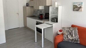 Une cuisine de taille réduite, dotée d’un plan de travail blanc, d’un grille-pain et d’une machine à café.