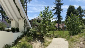 Un chemin de gravier mène à une maison dotée d’un toit en pente et d’une façade blanche.