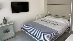 Une chambre à coucher moderne, équipée d’un lit, d’un téléviseur à écran plat, d’une table de chevet et d’une lampe fixée au mur.