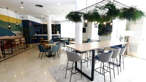Un comedor moderno con una mesa central, sillas alrededor y plantas colgantes.