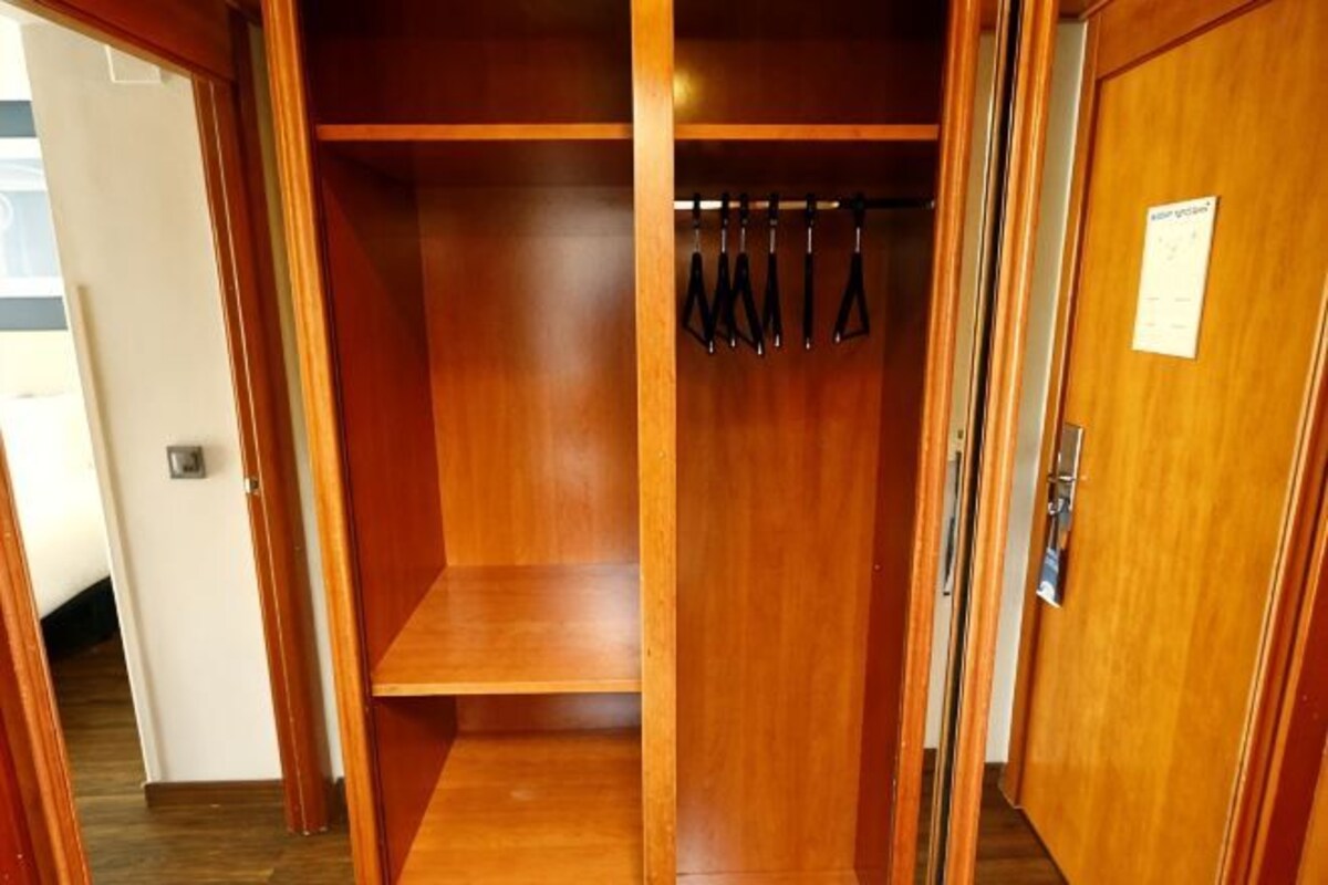 Un armario de madera con espacio para colgar y una puerta con un letrero.