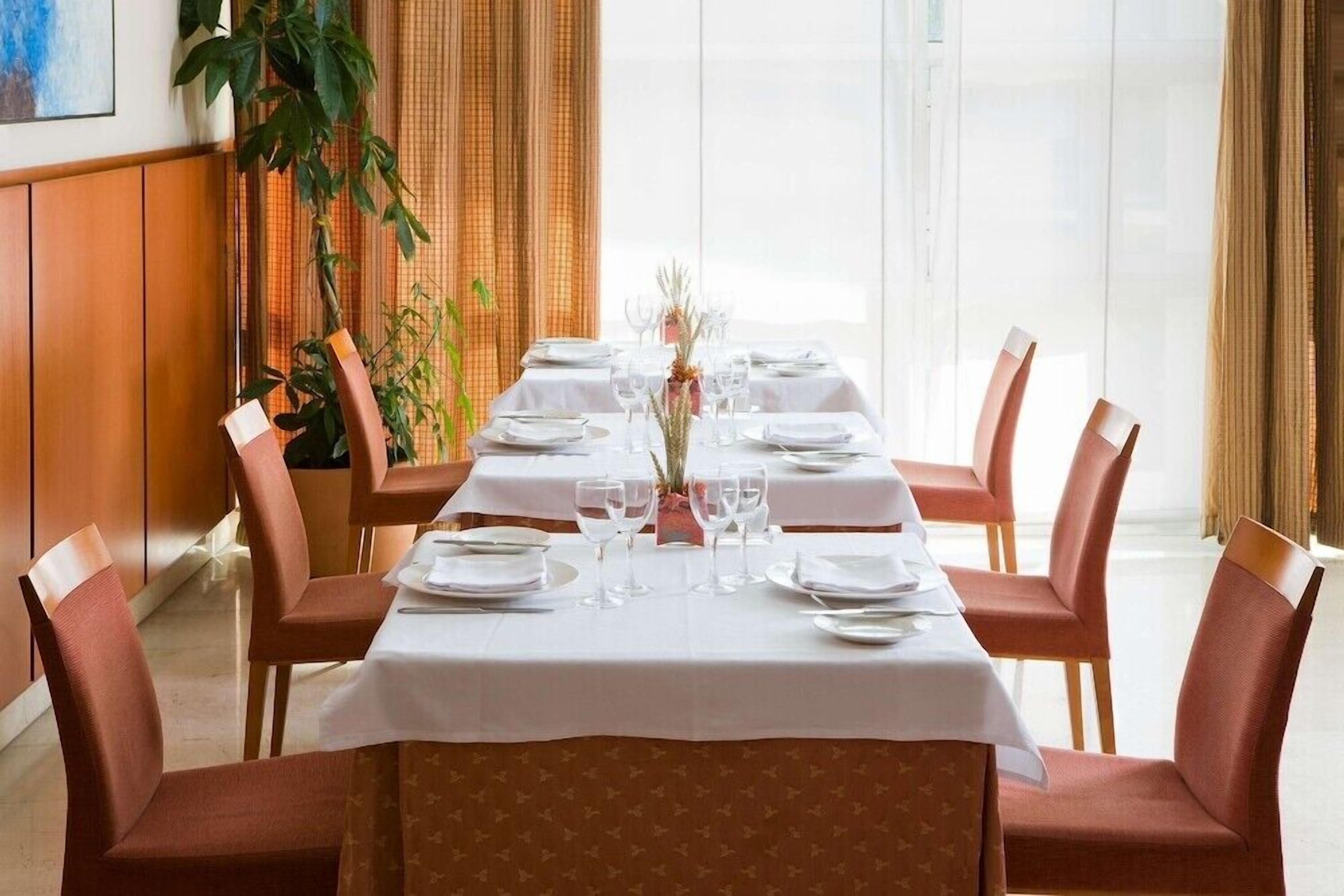 Un comedor con una mesa larga dispuesta para seis personas, rodeada por seis sillas.