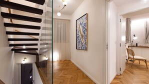 Un interior moderno con una escalera, piso de madera, un cuadro y una silla.