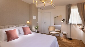 Una habitación de hotel con una cama grande, una mesita de noche con lámpara, una silla, una pequeña mesa con un jarrón de flores y un armario.