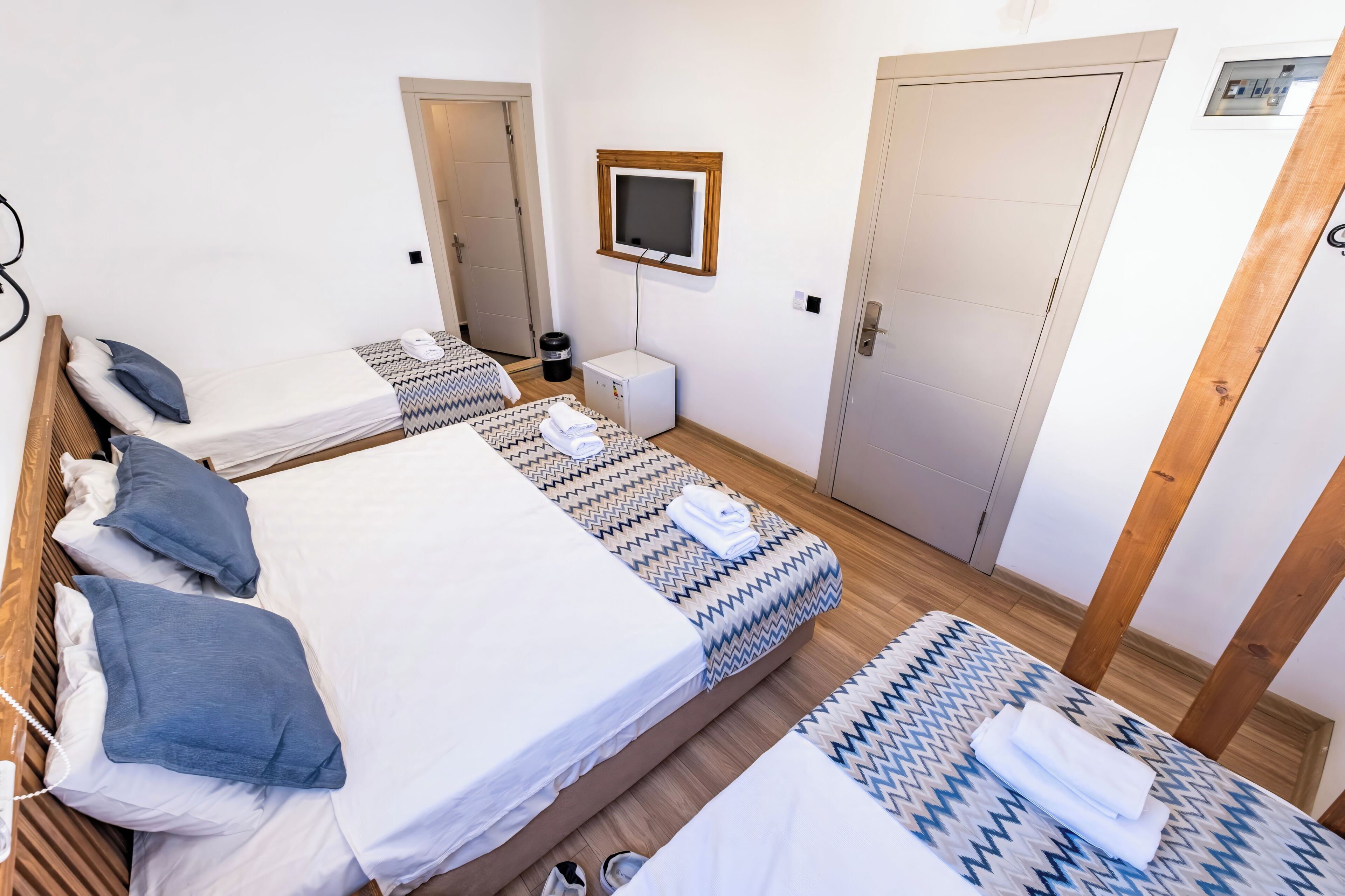 Habitación de hotel con dos camas, televisión, escritorio pequeño y puerta.