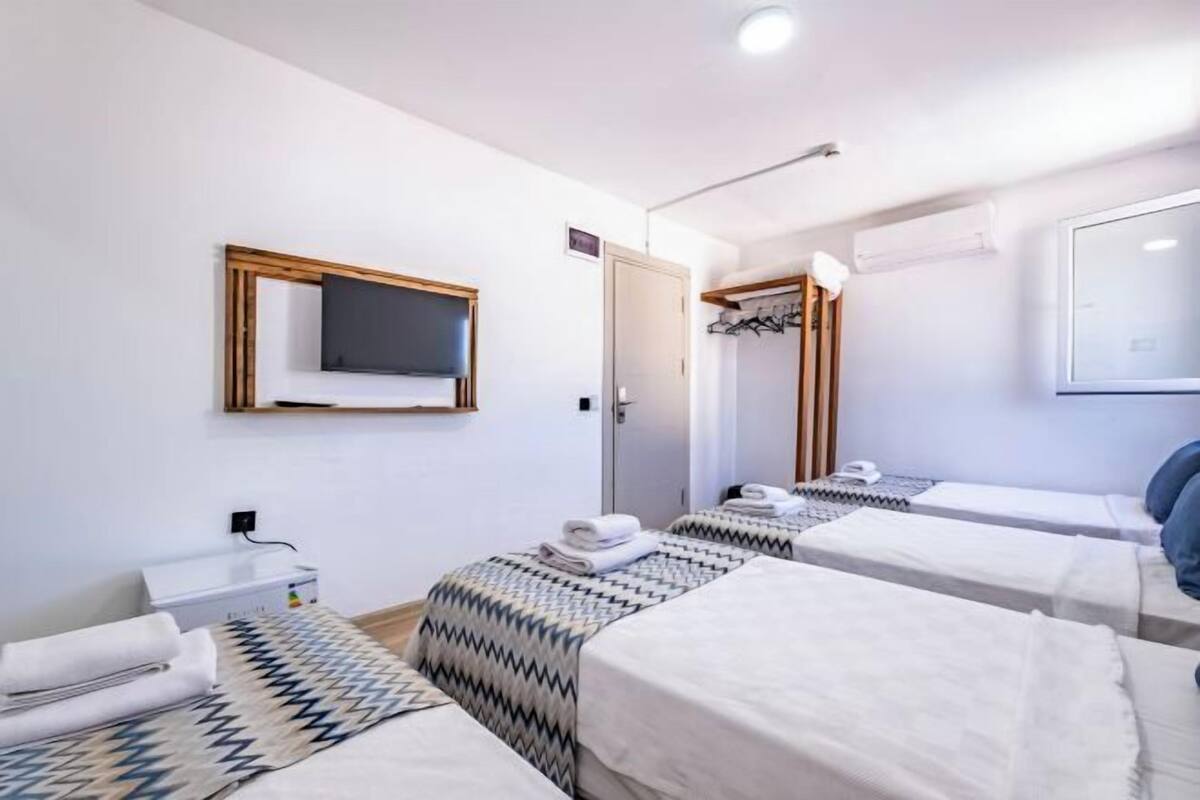 Una habitación de hotel con dos camas, un televisor en la pared, un espejo y un armario.
