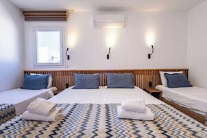 Quarto de hotel com duas camas, uma janela, ar condicionado e luzes fixadas na parede.