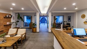 A reception area with a wooden desk, a laptop, and a seating area with chairs. - Costa Viva Bodrum (Bodrum)