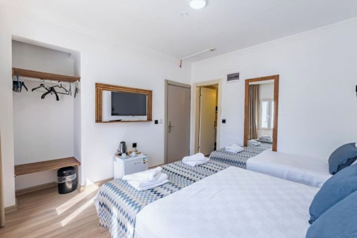 A hotel room with two beds, a TV, a desk, and a wardrobe.