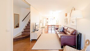 Una sala de estar moderna con una escalera, un comedor y una cocina.