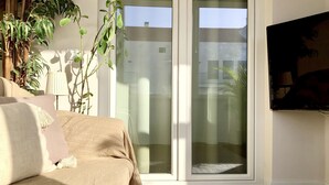 Un soggiorno moderno con divano, televisore e una porta scorrevole in vetro che dà su una zona esterna.