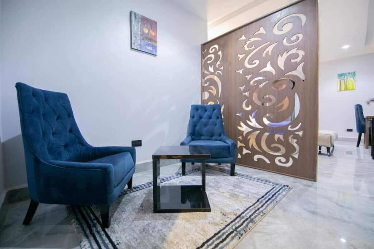 A room with two blue armchairs, a glass coffee table, and a decorative wooden partition.