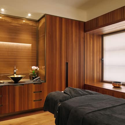 A modern bathroom with wooden paneling, a sink with a vessel basin, a towel rack, and a window with a view.