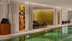 Ein moderner Wellnessbereich mit Wand in geometrischem Muster, einer Statue und einem Glaspool.
