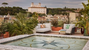 Ein Pool auf dem Dach mit Sternenmuster, umgeben von Blumentöpfen und Gartenmöbeln.